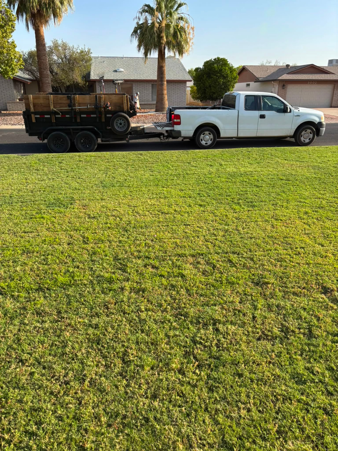 North Phoenix Lawn Maintenance truck and trailer parked at a freshly mowed residential lawn